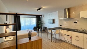 Et moderne hotelværelse med en træseng, et skrivebord, et spiseområde og et tekøkken.