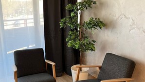Et moderne værelse med to grå polstrede stole, en potteplante og en aircondition på væggen.
