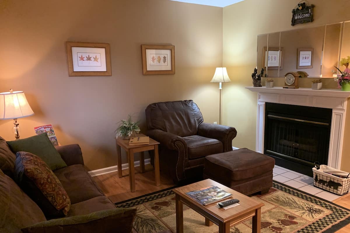 A cozy living room with a leather sofa, a wooden coffee table, and a fireplace.