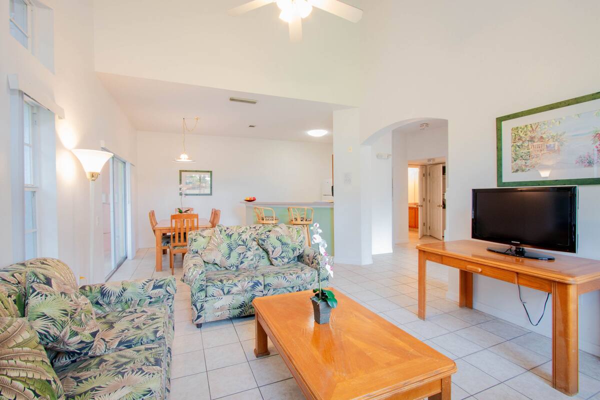 A spacious living area with a sofa, coffee table, and a flat-screen TV.