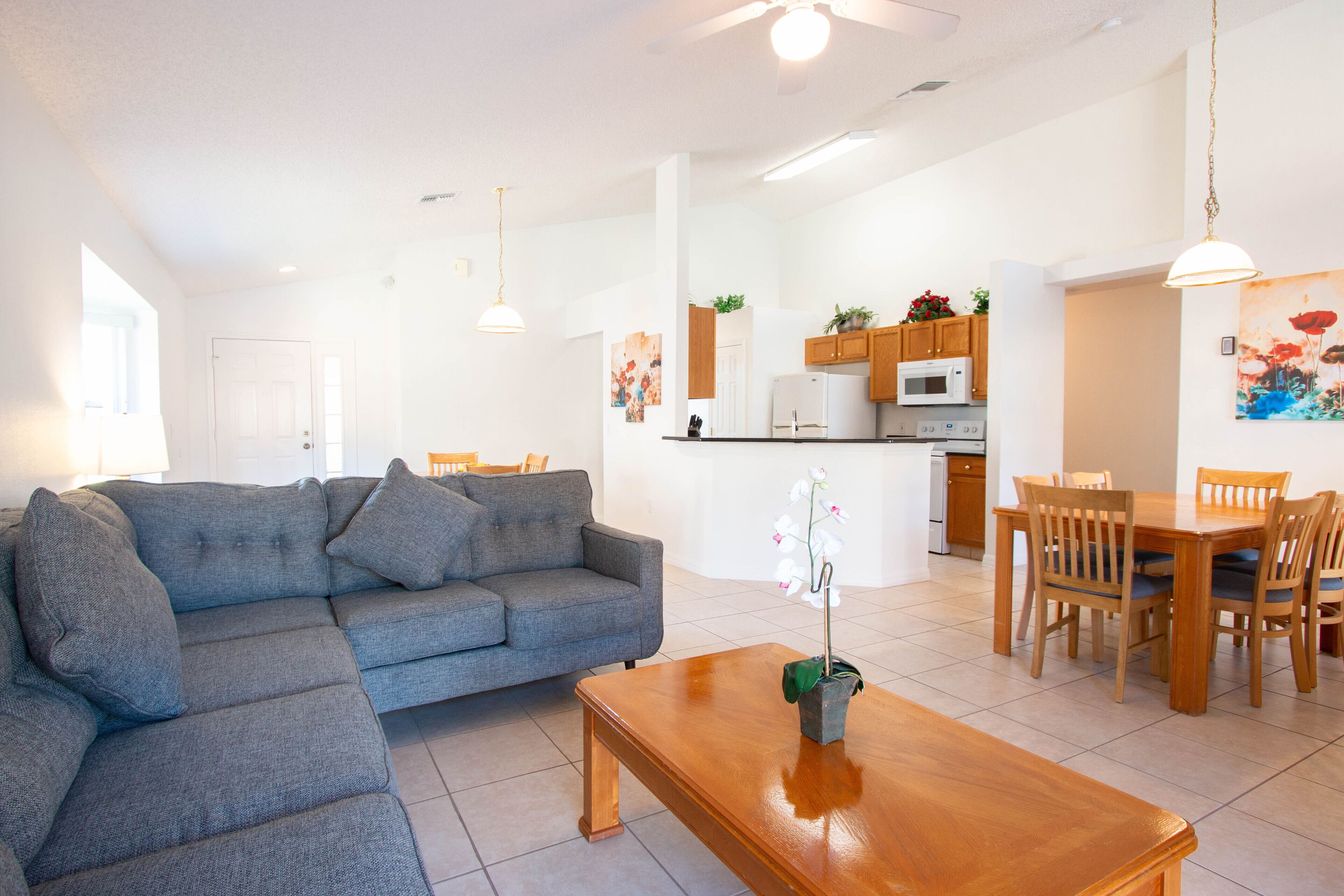 Ein modernes Wohnzimmer mit einem grauen Ecksofa, einem Holztisch und einem Essbereich mit Holzkästen und einem Tisch.