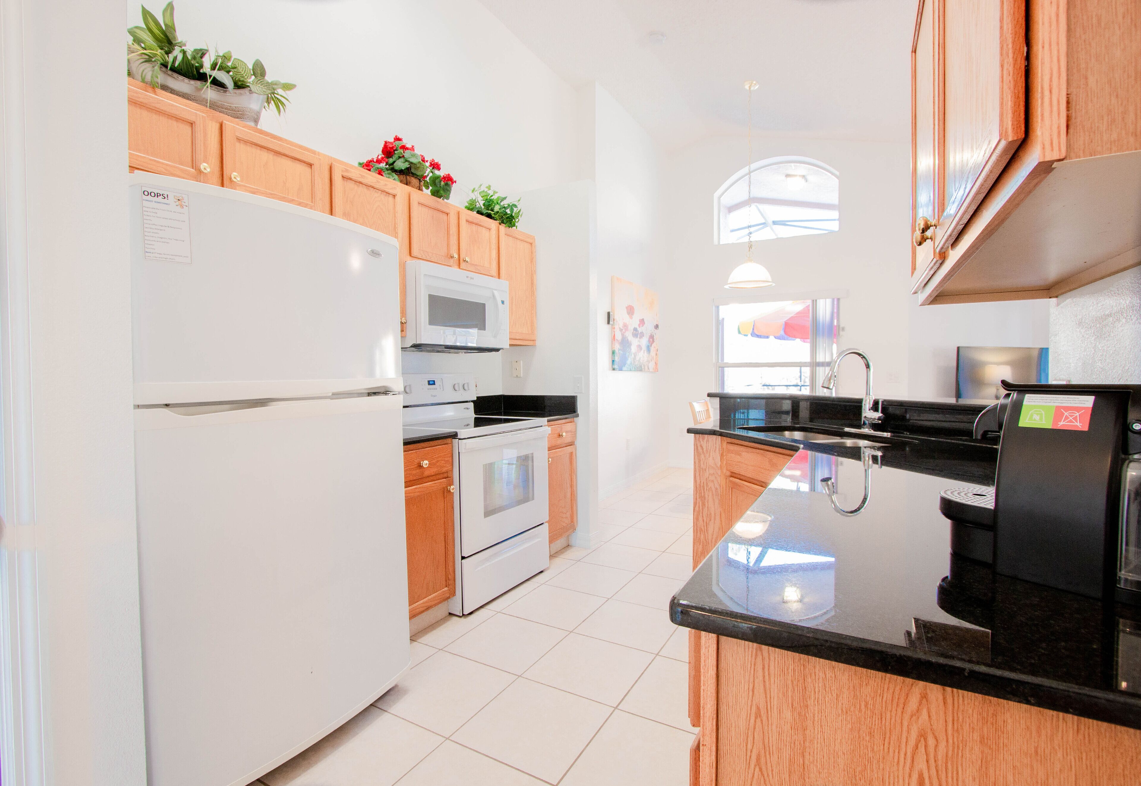 A modern kitchen with wooden cabinets, a white refrigerator, a microwave, an oven, and a coffee machine.