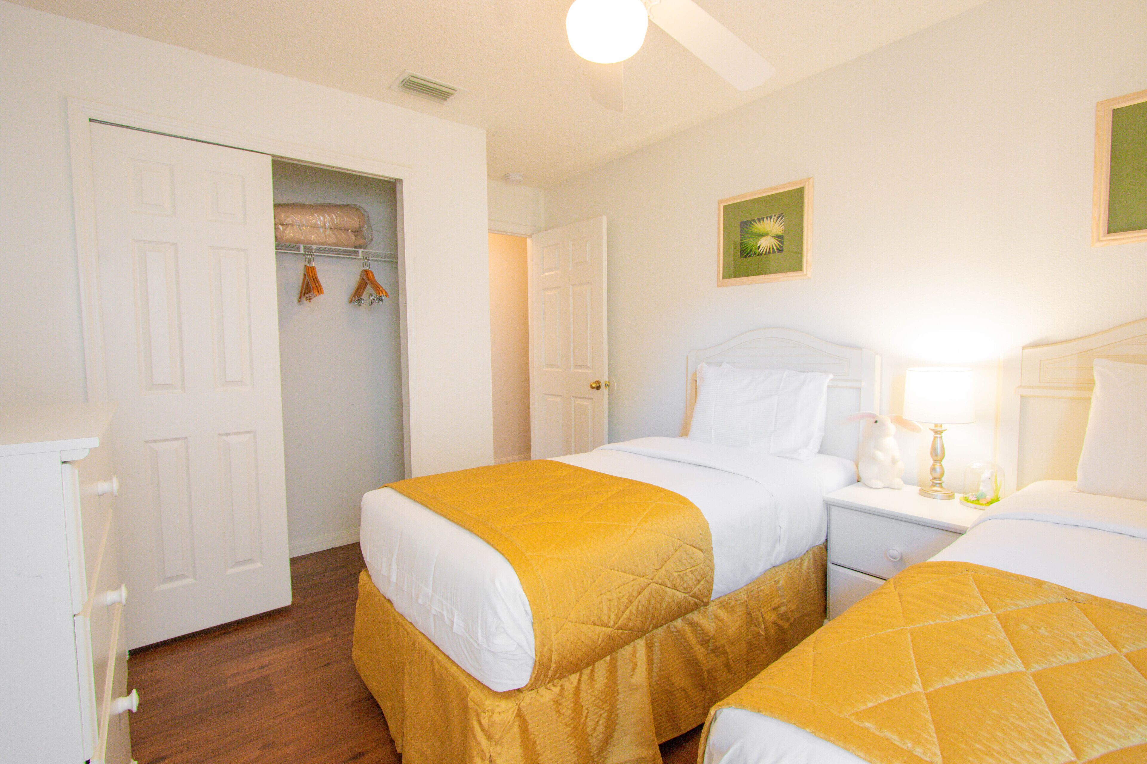 Una habitación de hotel con dos camas, un armario y una mesita de noche con lámpara.