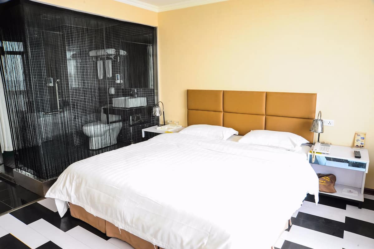 A hotel room with a large bed, a headboard, a nightstand, a lamp, and a wall-mounted phone.