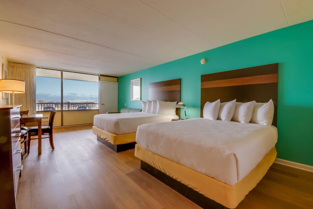 A hotel room with two beds, a desk, and a chair.