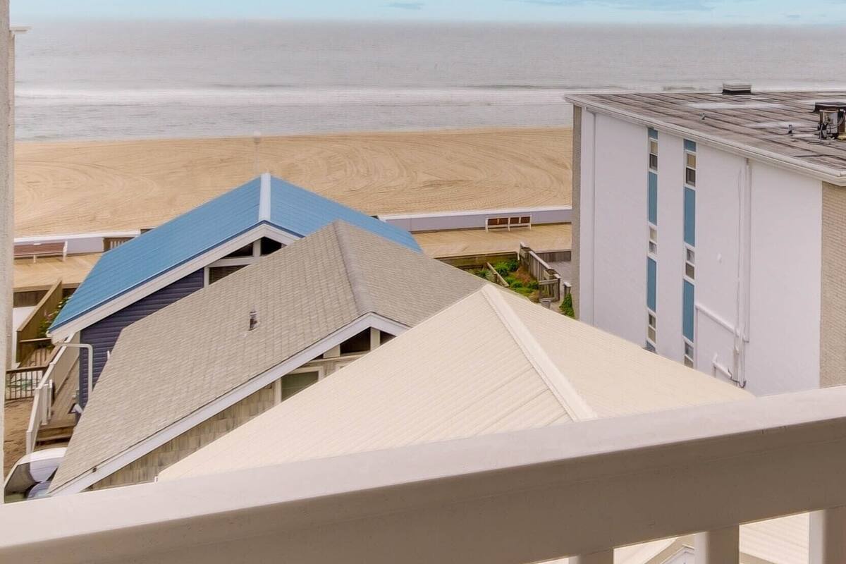 A view of a beach from a balcony with a clear sky.