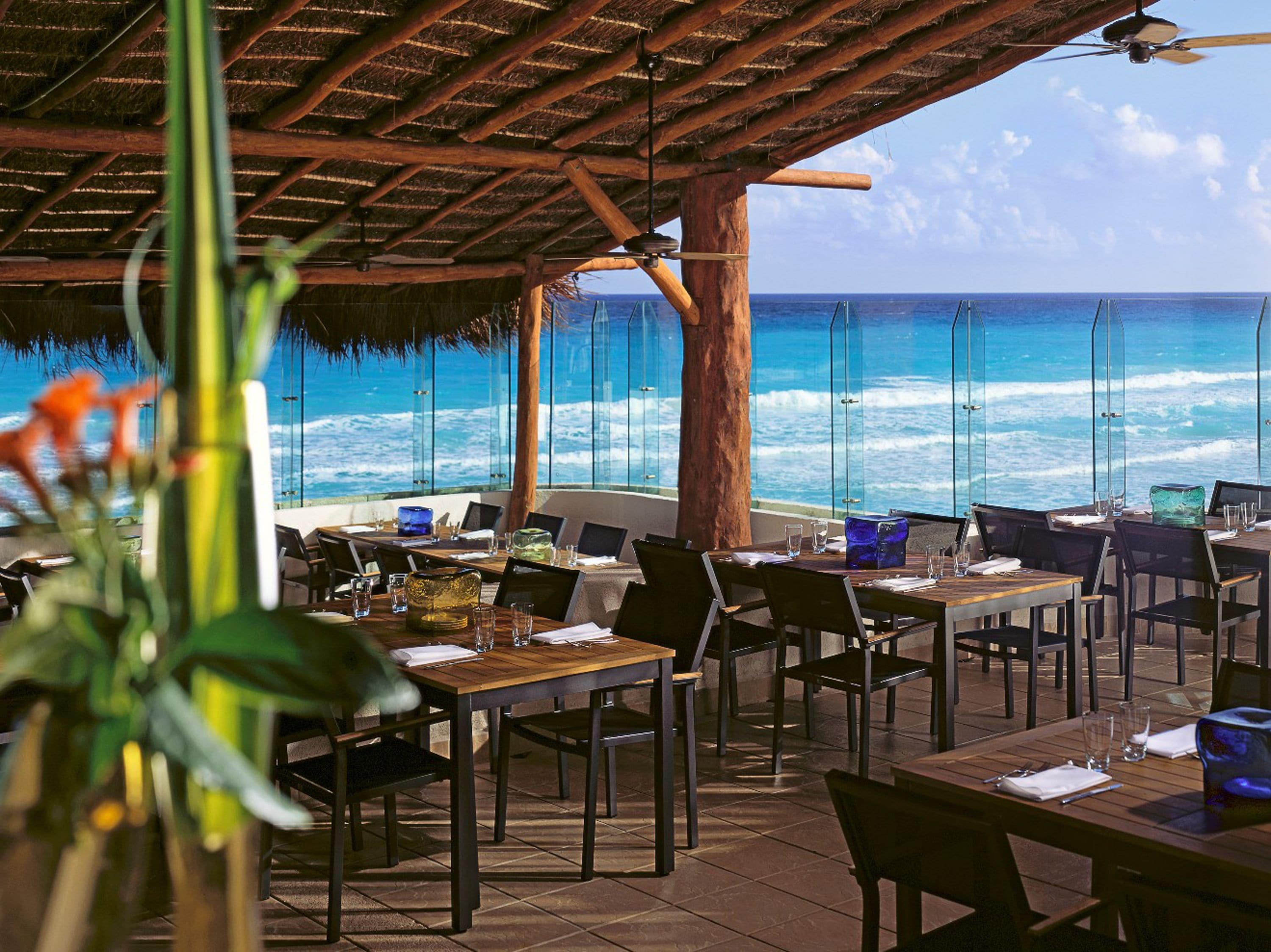 An outdoor dining area with tables and chairs, overlooking the ocean.