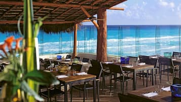 An outdoor dining area with tables and chairs, overlooking the ocean.