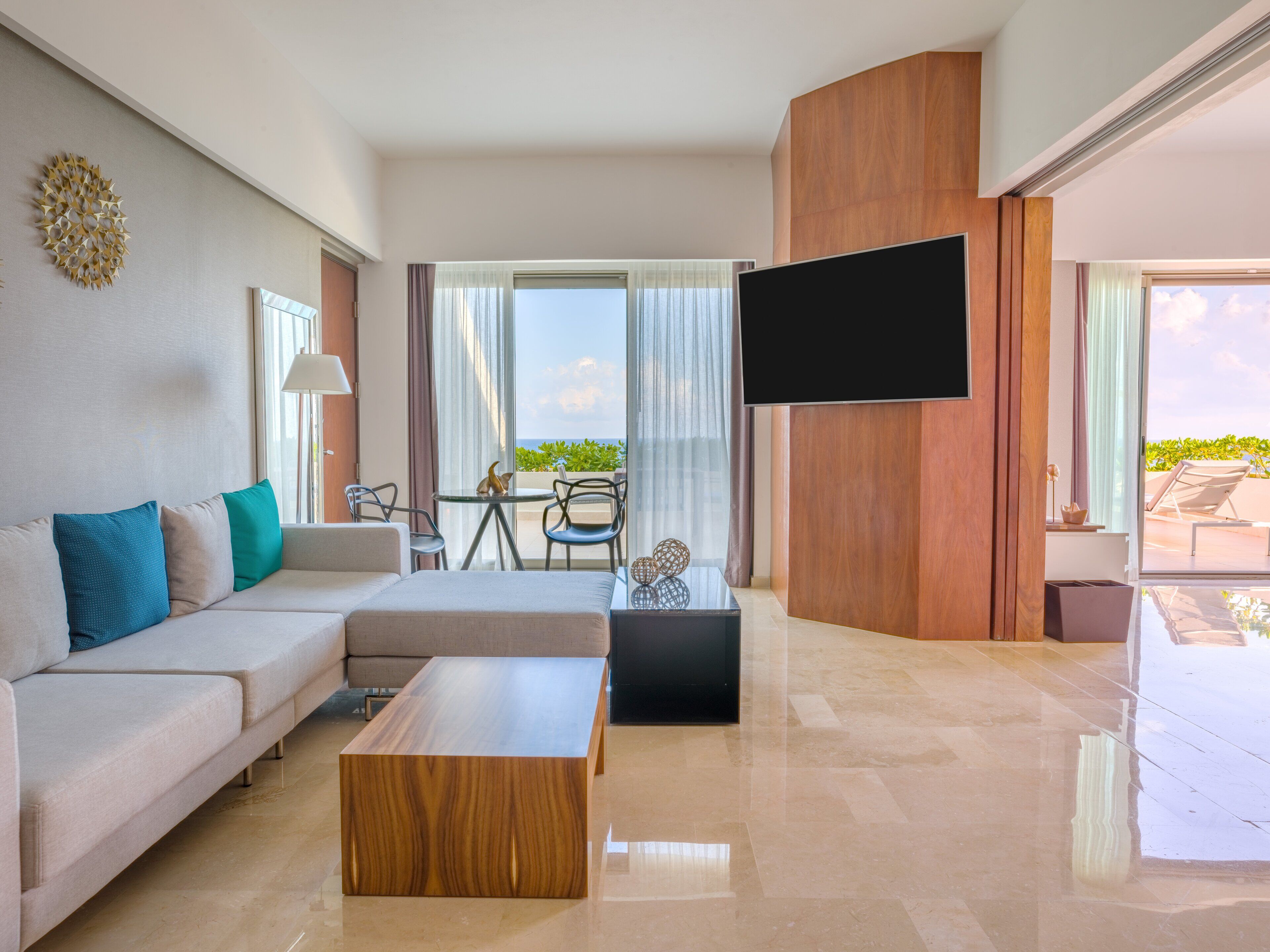 Un salon moderne avec un canapé, une table basse et un téléviseur à écran plat fixé au mur.