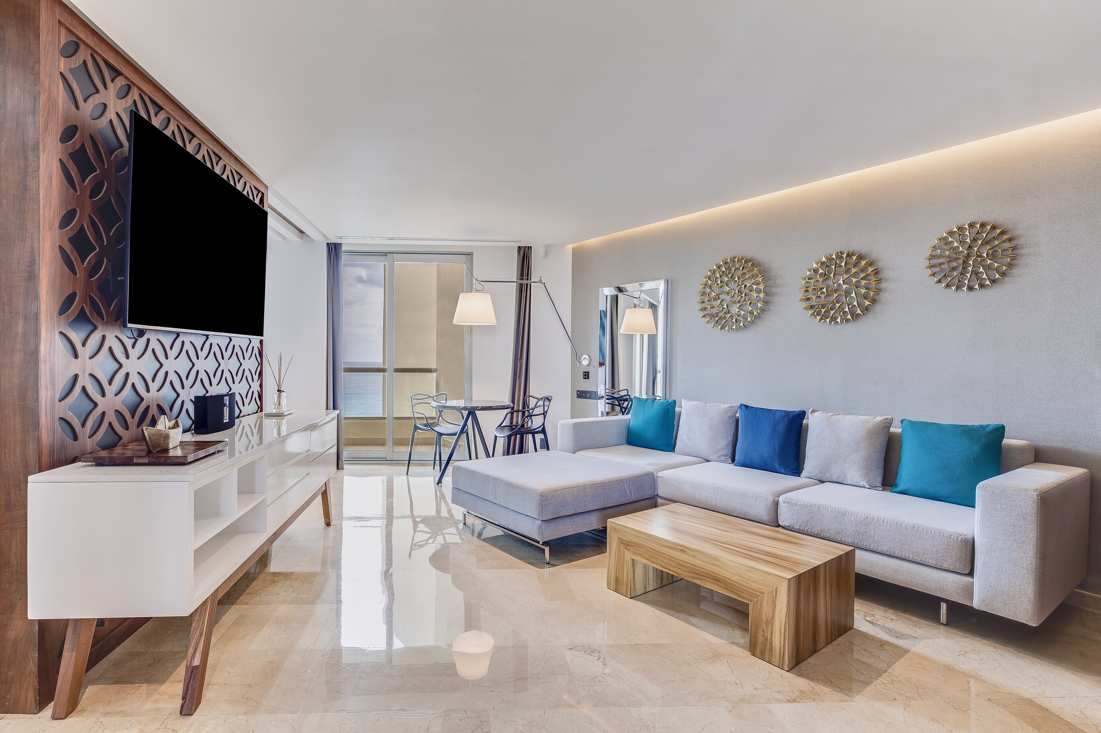A modern living room with a sectional sofa, a coffee table, a TV, and decorative wall art.