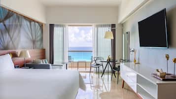 Una habitación de hotel con cama, escritorio, silla, televisor y vista al océano.