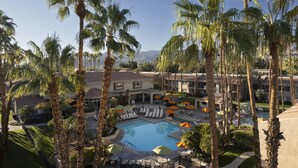 Un resort con piscina rodeada de palmeras y sillas de descanso.