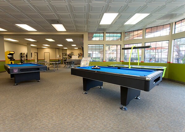 Une salle de billard équipée de deux tables de billard, d’un porte-billes et d’une table de ping-pong.