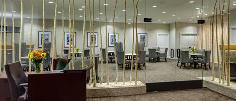 A modern conference room with a glass partition, multiple tables, and chairs.