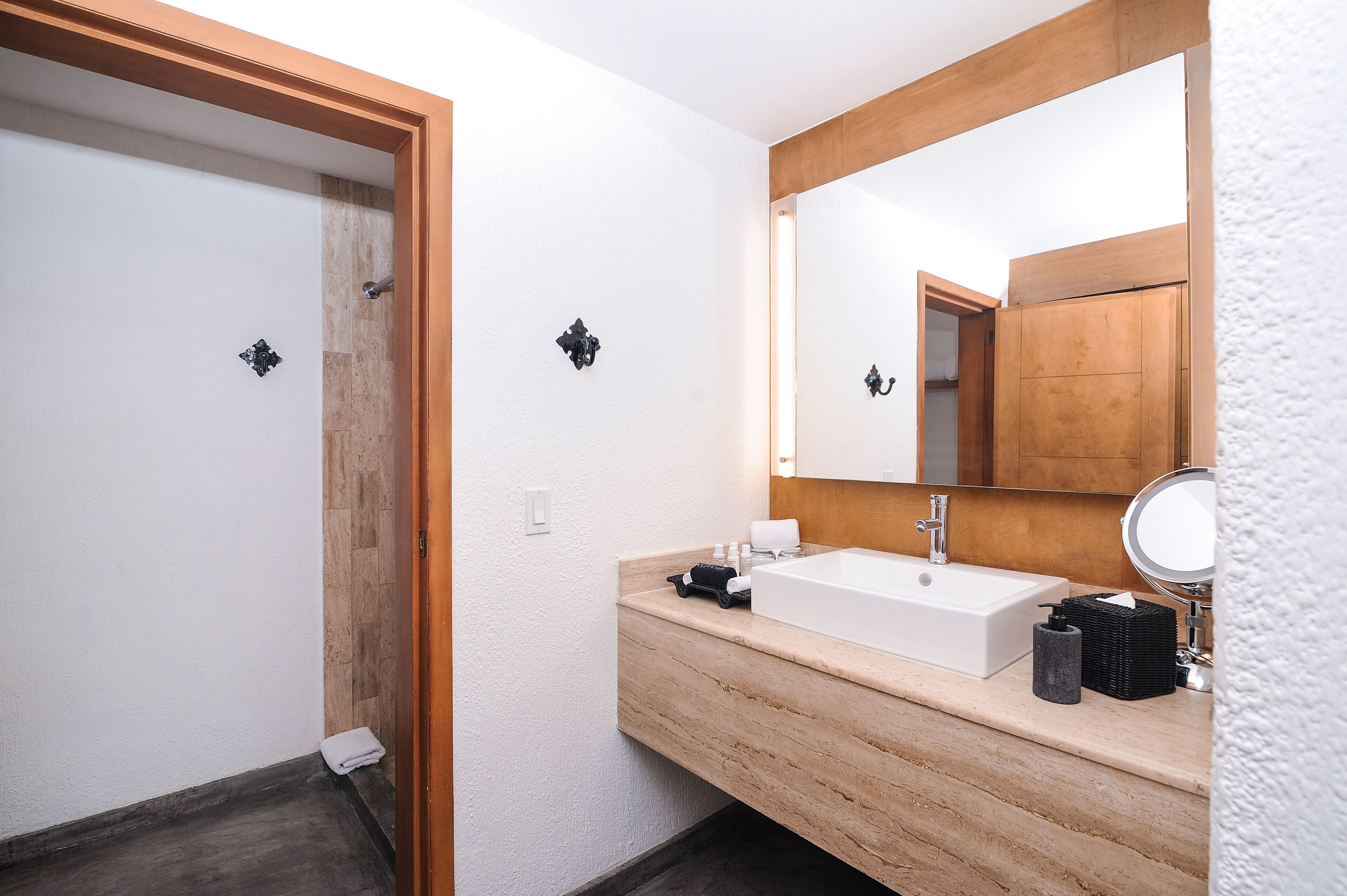 Un baño moderno con tocador de madera, un espejo grande y zona de ducha.