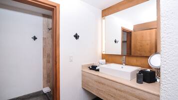 Un baño moderno con tocador de madera, un espejo grande y zona de ducha.