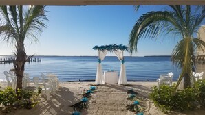 A beach wedding setup with a white arch and chairs facing the sea.