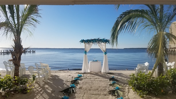 A beach wedding setup with a white arch and chairs facing the sea. - Princess Bayside Beach Hotel (Ocean City)