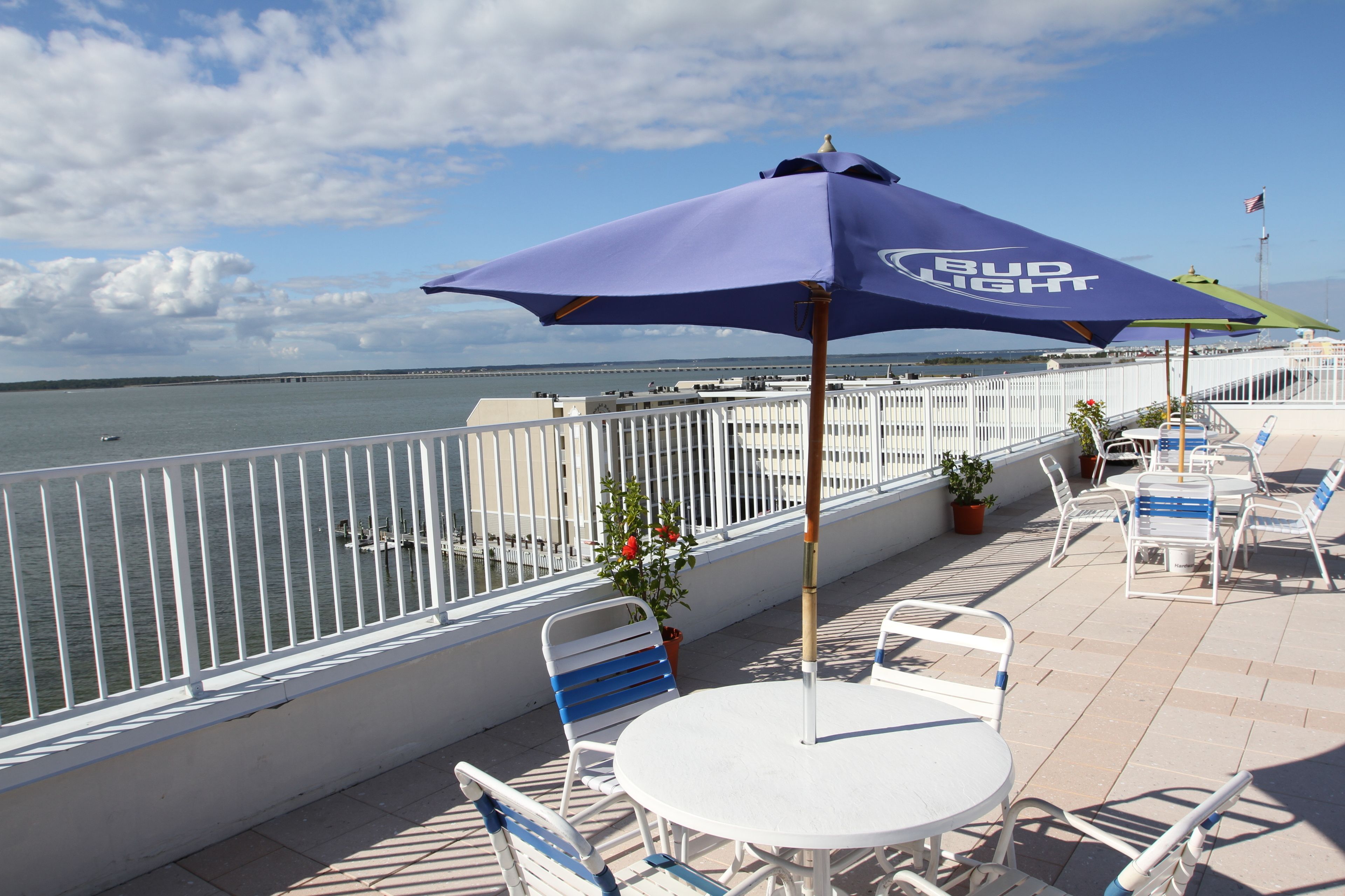 Terraza con vista al agua, barandas blancas y mobiliario exterior con la marca Bud Light.