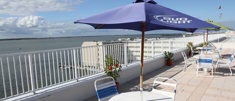Terraza con vista al agua, barandas blancas y mobiliario exterior con la marca Bud Light.