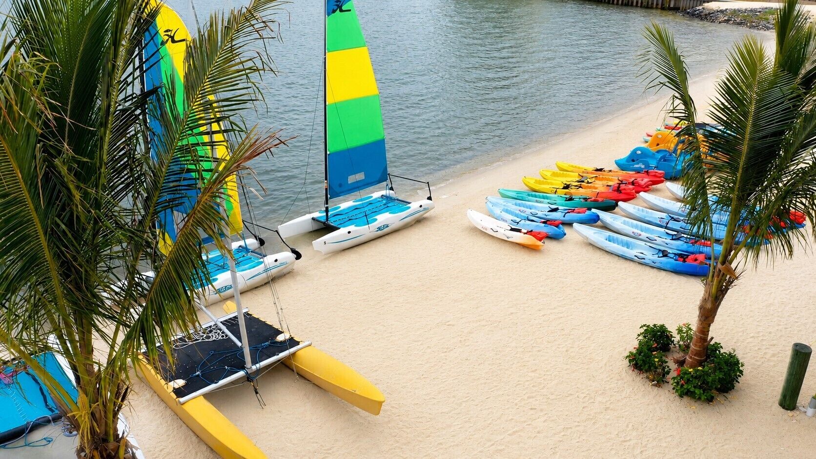 A beach with multiple kayaks and a sailboat.