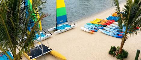 A beach with multiple kayaks and a sailboat.