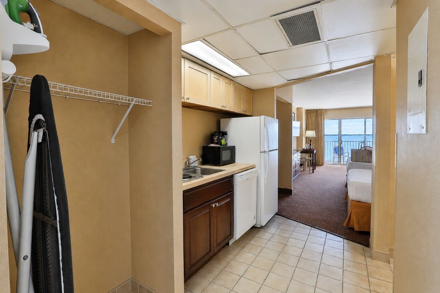 Quarto de hotel pequeno com cozinha compacta, uma cama, banheiro e vista para o mar.