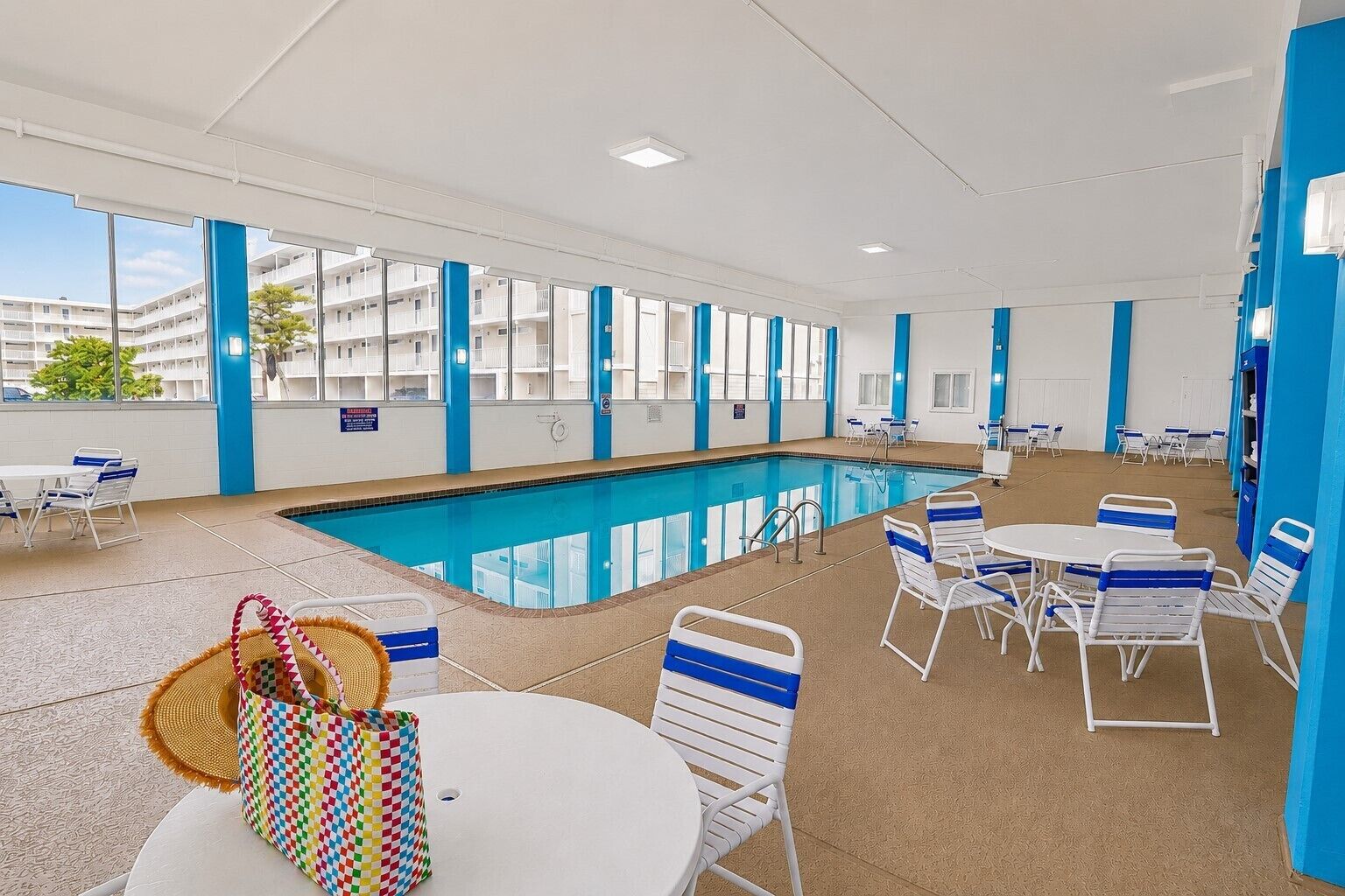 Une chambre d’hôtel avec piscine, des touches de couleur bleue et vue sur le bâtiment.