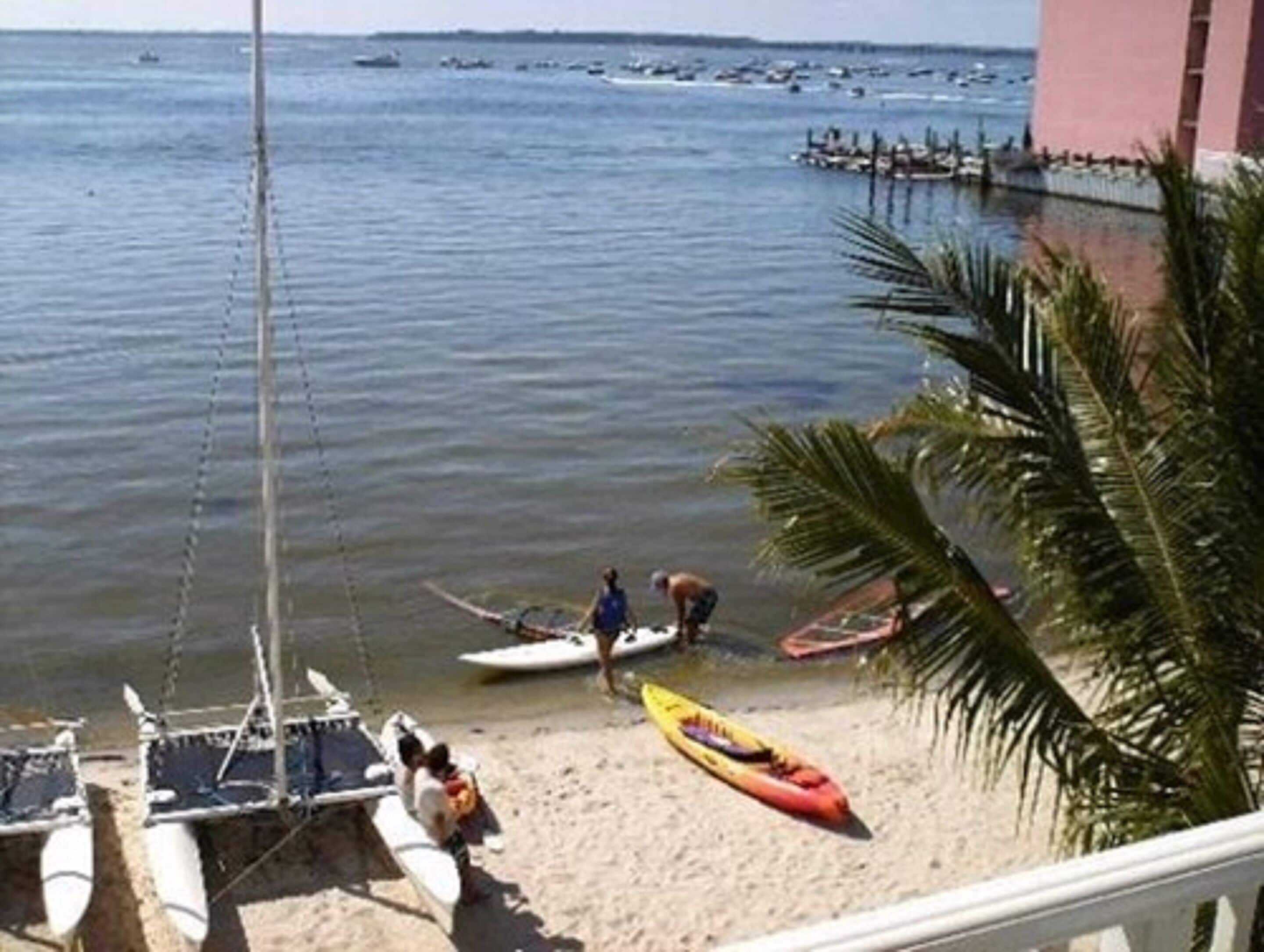 A beach with kayaks and a sailboat docked near the shore.