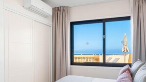 A hotel room with a large window, a bed, a wardrobe, and an air conditioning unit. - Club La Costa at the Paradise Club (Adeje)