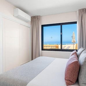A hotel room with a large window, a bed, a wardrobe, and an air conditioning unit. - Club La Costa at the Paradise Club (Adeje)