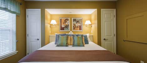 Habitación de hotel con una cama grande, dos lámparas fijadas a la pared y dos cuadros con flores sobre la cama.