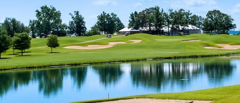 A golf course with a pond, sand bunkers, and trees.
