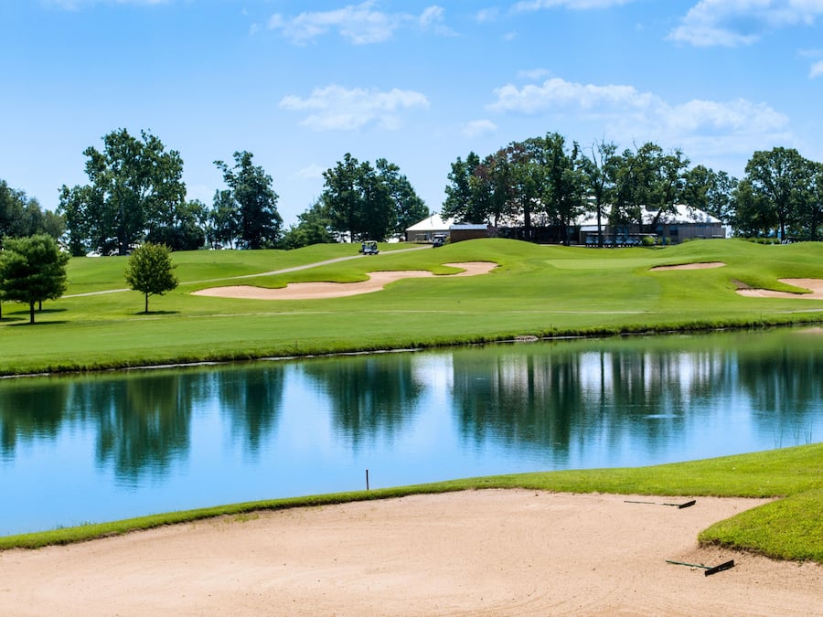 A golf course with a pond, sand bunkers, and trees.