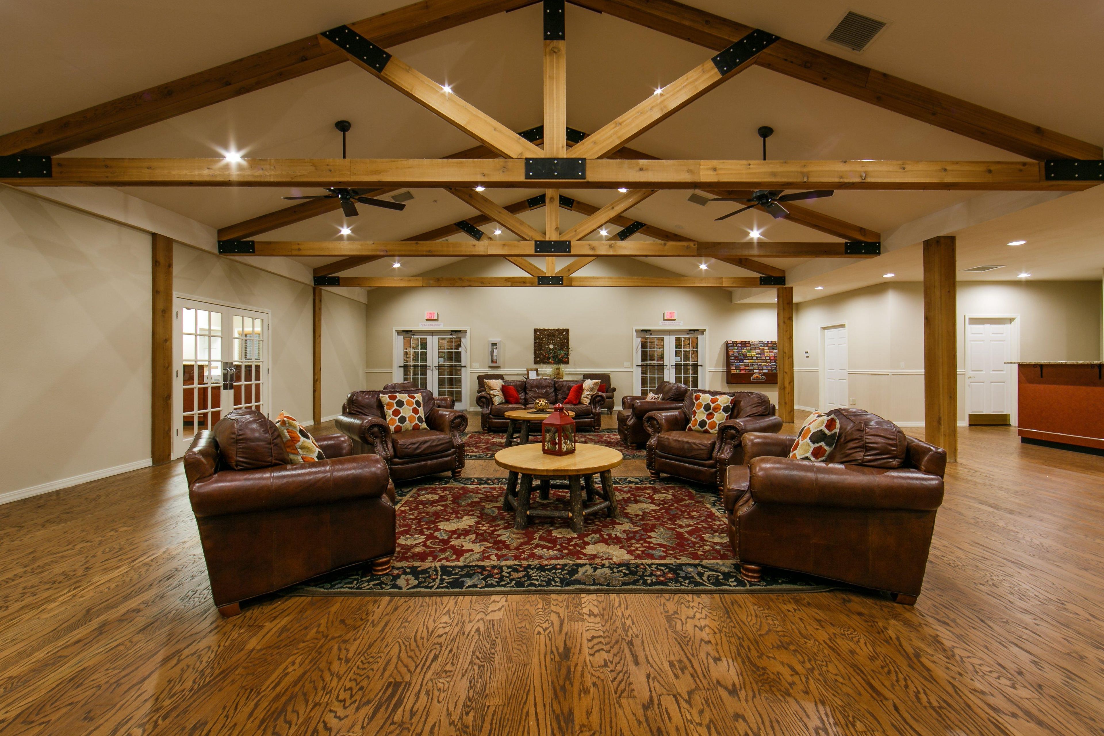 A spacious living room with leather sofas, a central coffee table, and a high wooden ceiling with exposed beams.