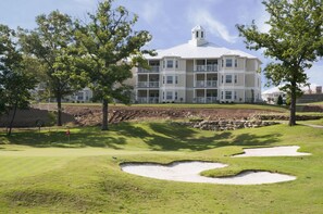 A multi-story building with a flat roof and balconies, surrounded by trees and a well-maintained golf course. - Holiday Hills Resort at Branson (Branson)