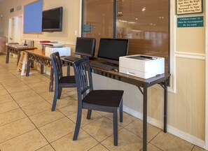 A computer lab with desks, chairs, and a large monitor.