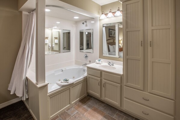 A bathroom with a bathtub, two sinks, and a large mirror. - Holiday Hills Resort at Branson (Branson)
