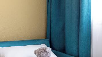 A bed with a teal headboard, a white pillow, and a plush teddy bear.
