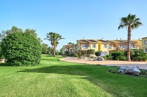 Una zona residencial con varias casas de dos pisos, césped bien cuidado y palmeras.