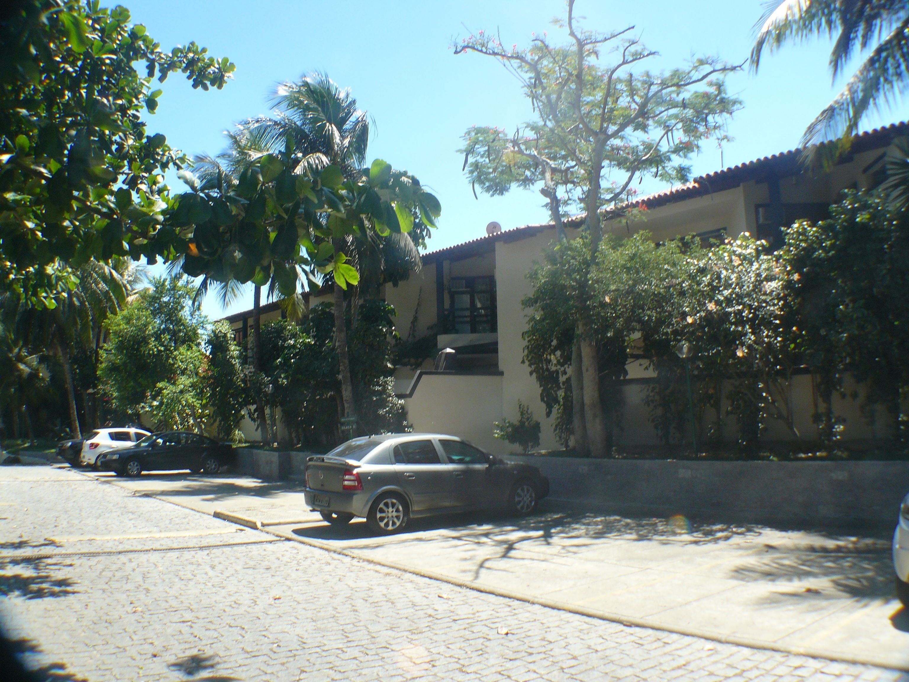 Una calle con un coche estacionado, un edificio de techo con tejas y árboles.