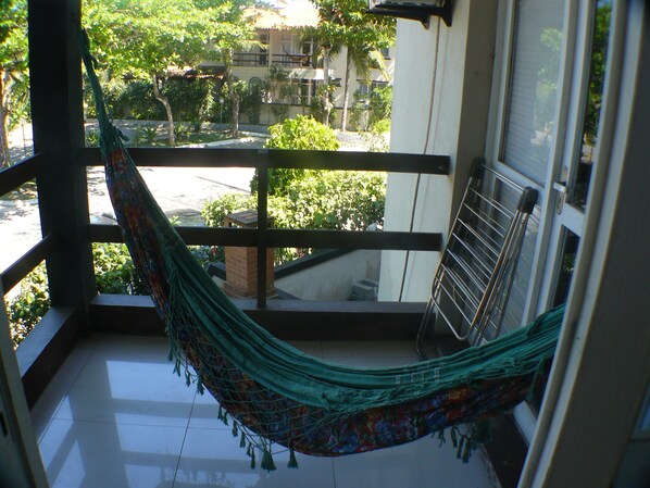 Un hamac sur un balcon donnant sur un quartier résidentiel.