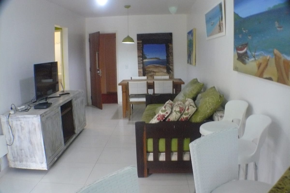 Una sala de estar con televisor, mesa de comedor y sofá.