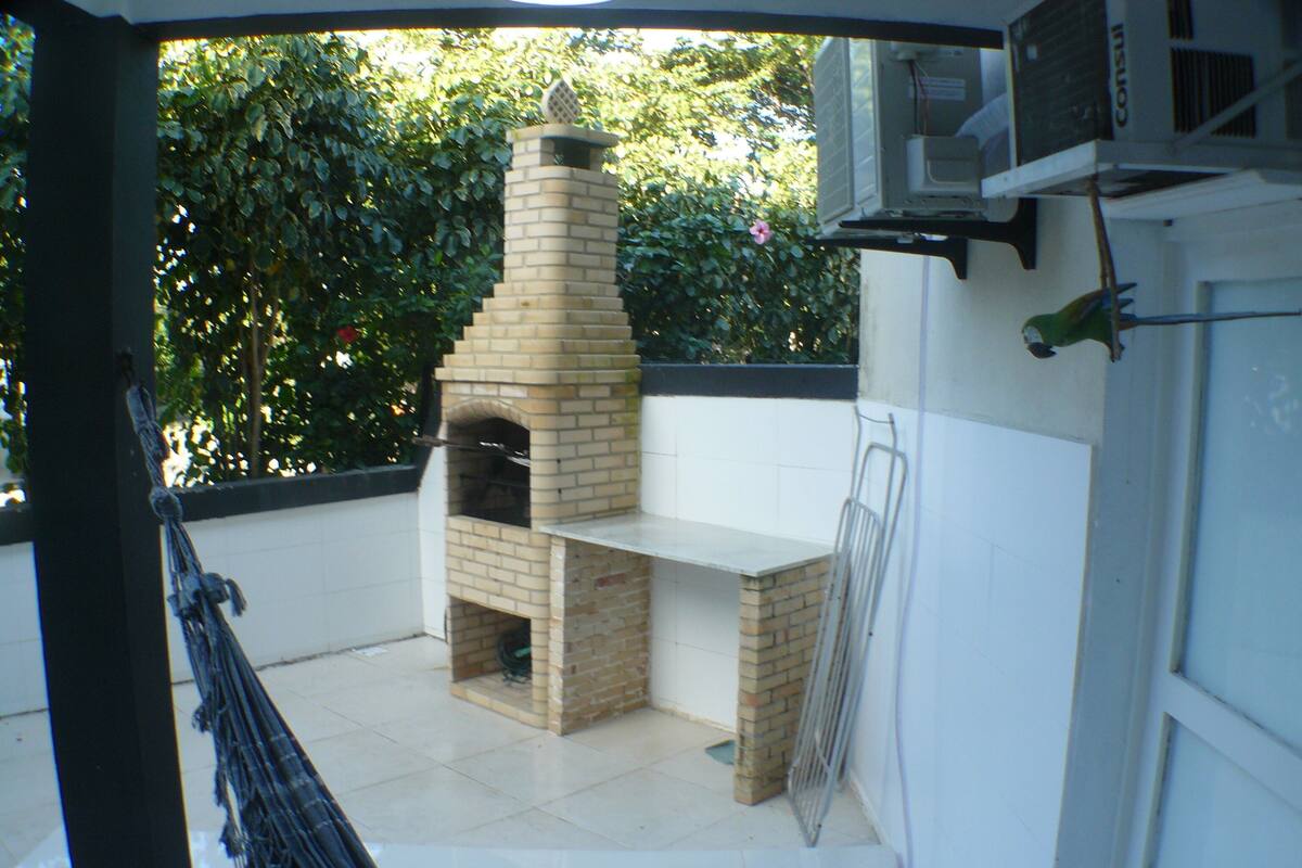 Un horno de ladrillo al aire libre con chimenea, una parrilla metálica y una zona de patio con baldosas.