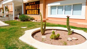 An aparthotel with a sign, cacti, and a well-maintained lawn. - Aparthotel Acuasol (Peniscola)