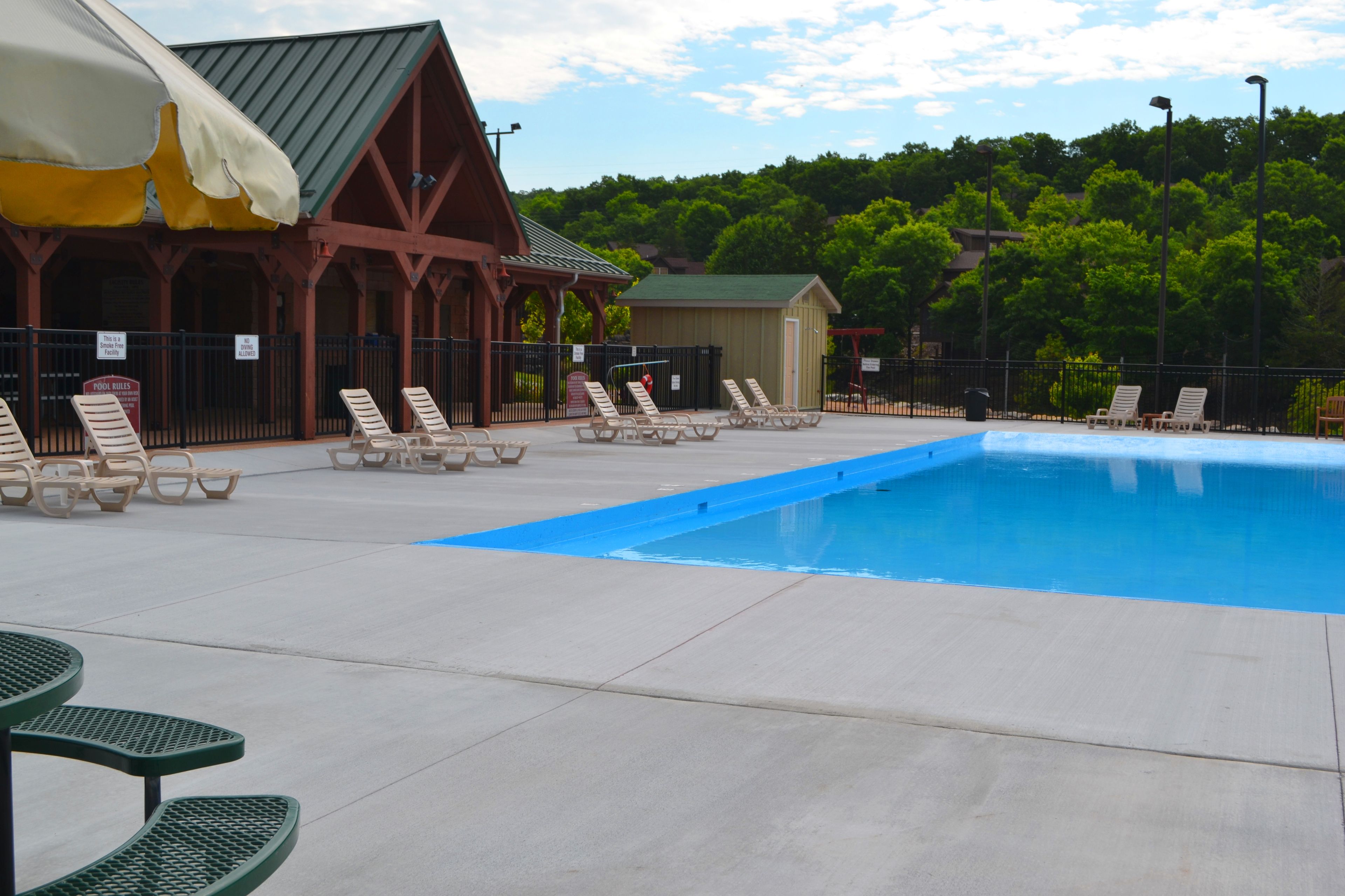 A swimming pool area with lounge chairs and a covered seating area.