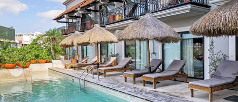 Alberca al aire libre, sombrillas en la alberca y camastros