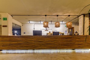 Un área de recepción con un mostrador de madera, iluminación colgante y un cartel que dice