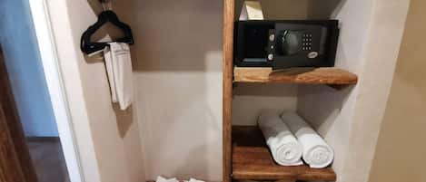 Een houten schapunit met een magnetron, handdoeken en een badjas.