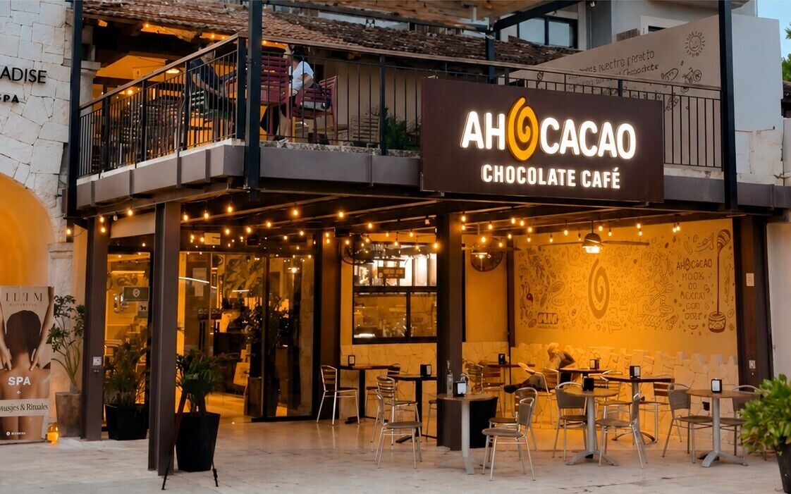A chocolate-themed café with outdoor seating and a sign that reads 'AHOCACAO CHOCOLATE CAFÉ'.